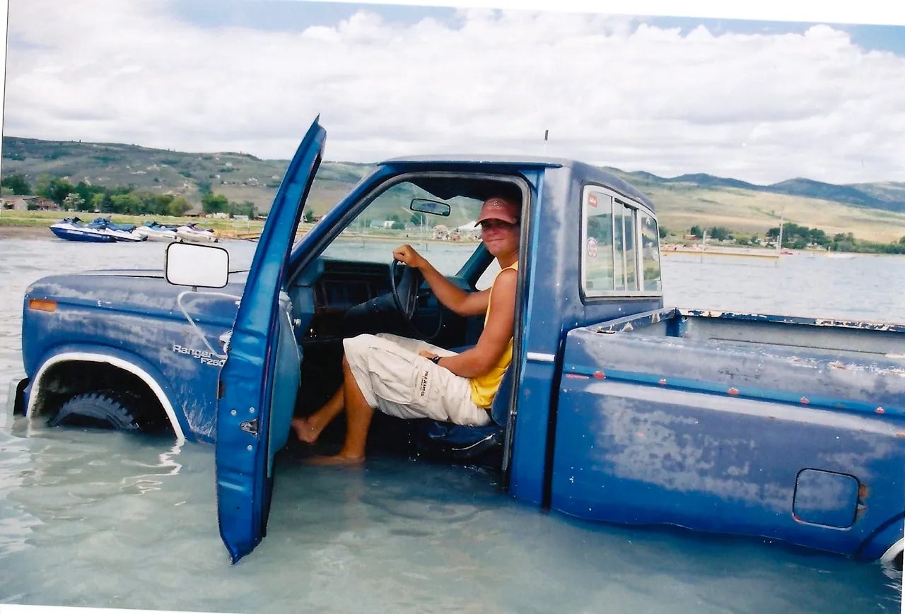 A pickup truck bed in steady rain showing water beading and running off a closed hard cover