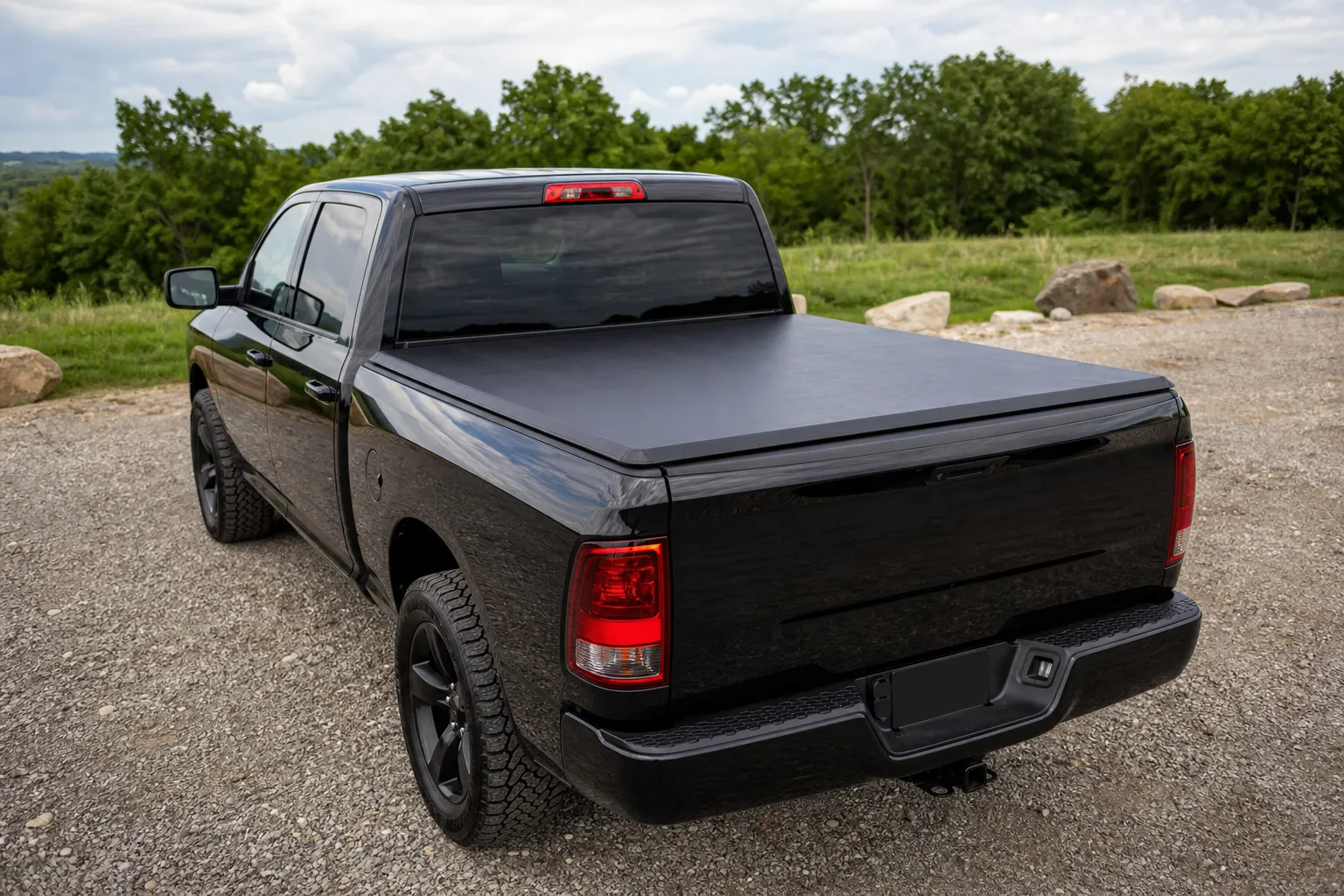 [Black soft roll-up tonneau cover installed and closed over a full-size pickup truck bed, parked outdoors in daylight]