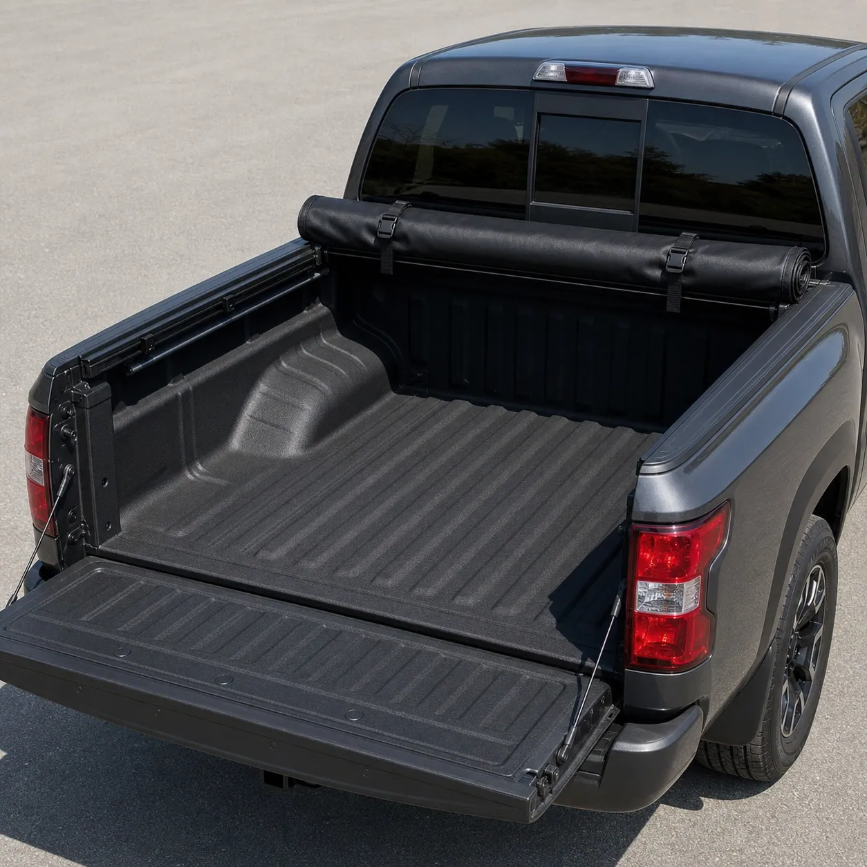 Black soft roll-up tonneau cover rolled forward against the cab of a Nissan Frontier with the open bed visible