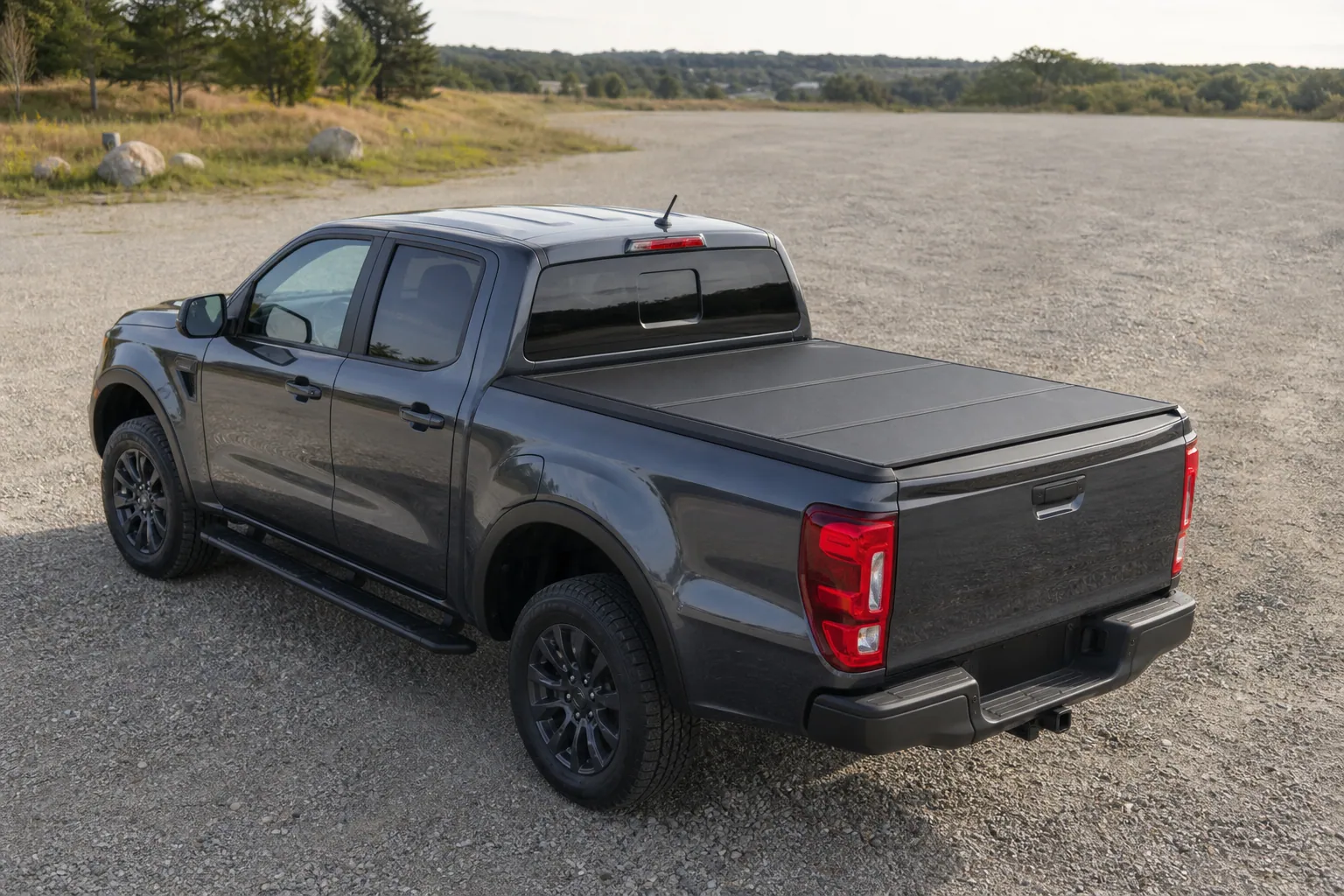 Ford Ranger with a black hard folding tonneau cover closed over the 5-foot bed, rear three-quarter view