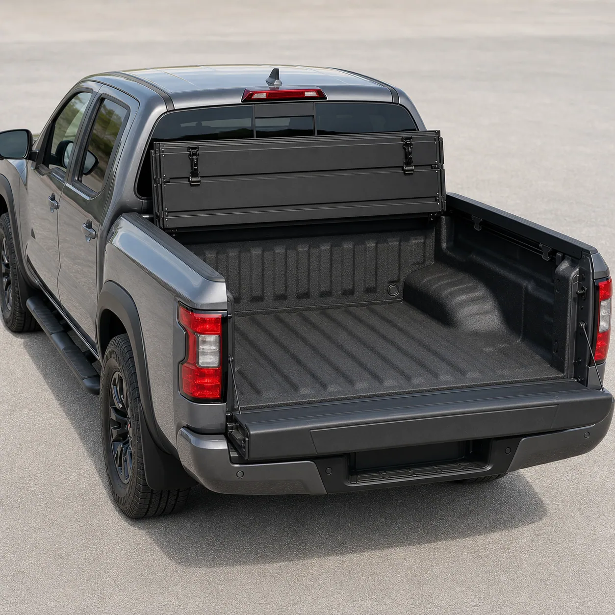 Matte-black BAKFlip MX4 hard folding tonneau cover folded forward against the cab on a Nissan Frontier bed