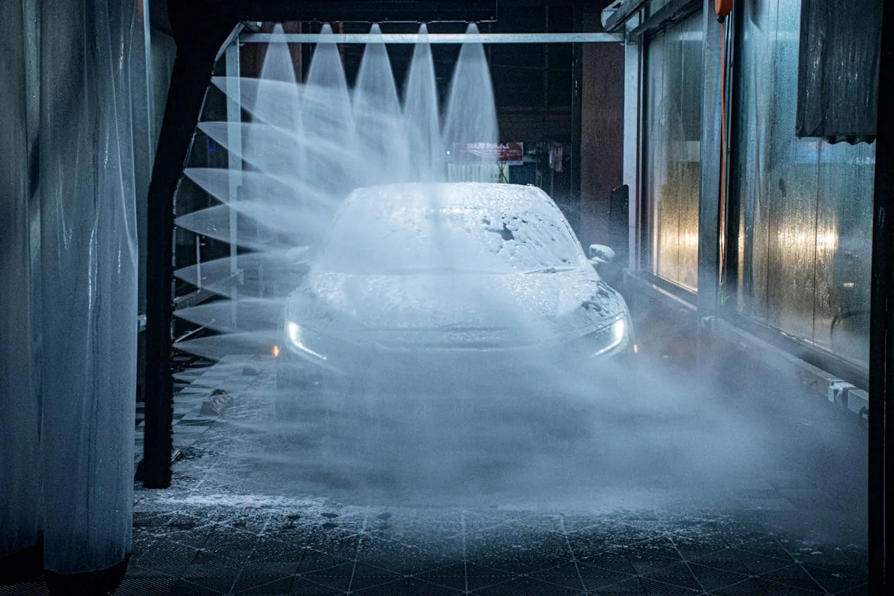 [Pickup truck with a tonneau cover passing through an automatic car wash with brushes and spray]