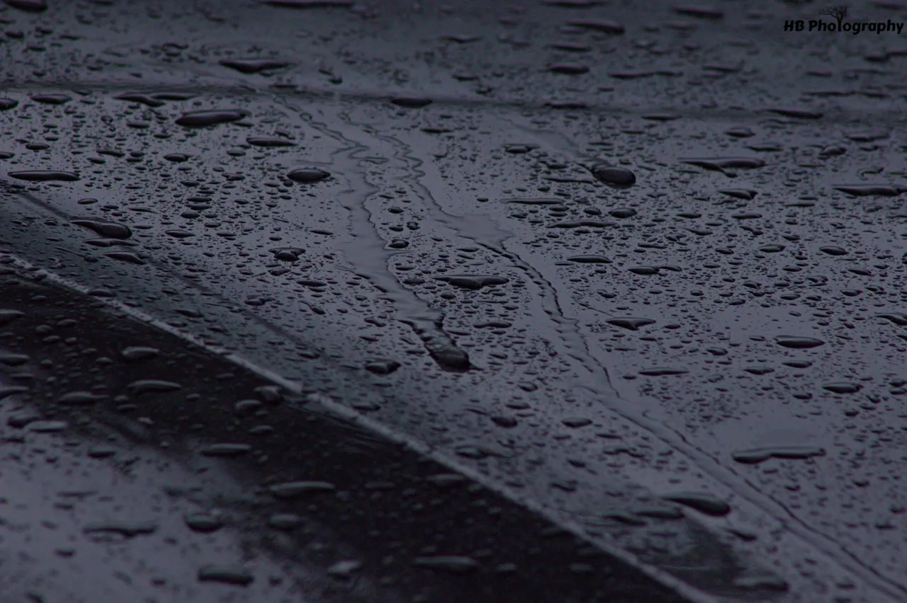 [Rain beading and rolling off the surface of a black vinyl tonneau cover during a rainstorm]
